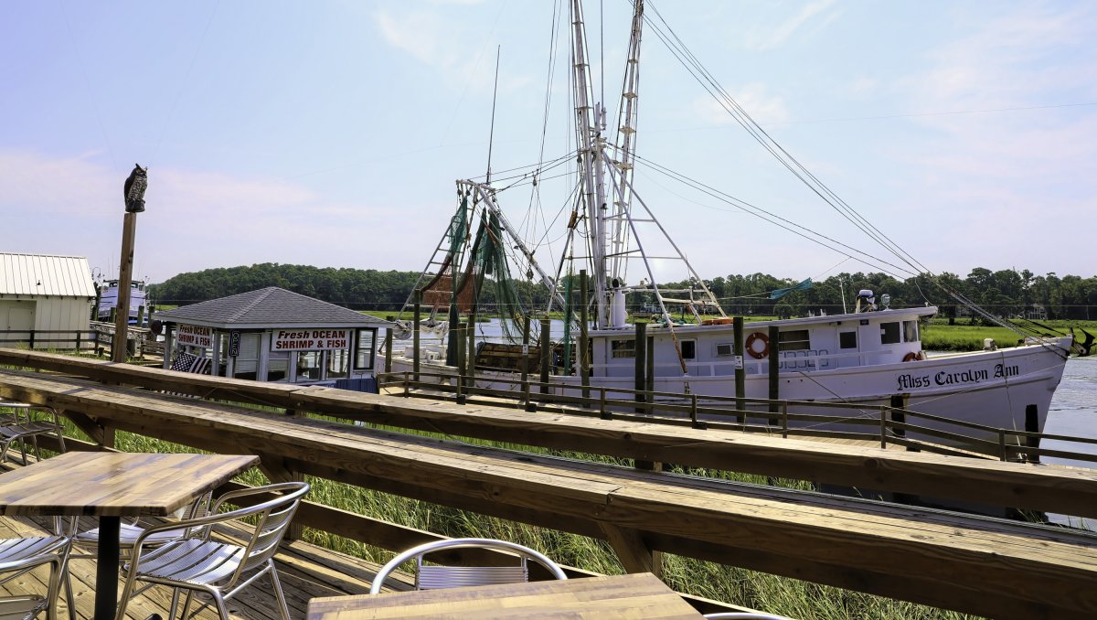 Fishing boat docked in water outside restaurant patio 