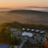 Aerial of farm stay with cabins and main house with forest in background