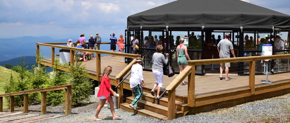 People enjoying views at covered bar atop a mountain with longrange mountain views