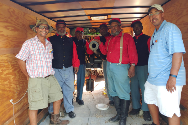 Group of men standing around a canon posing for photo