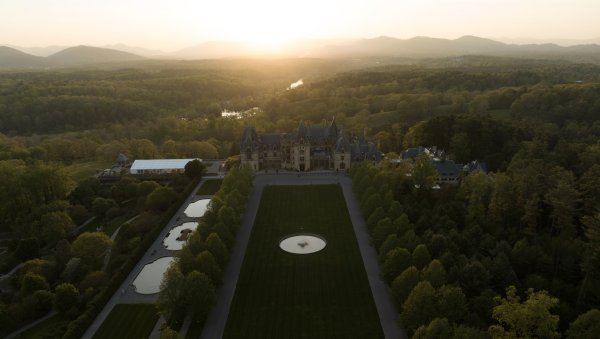 Aerial of vast Biltmore grounds and estate with mountains in background