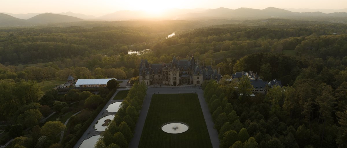 Aerial of vast Biltmore grounds and estate with mountains in background