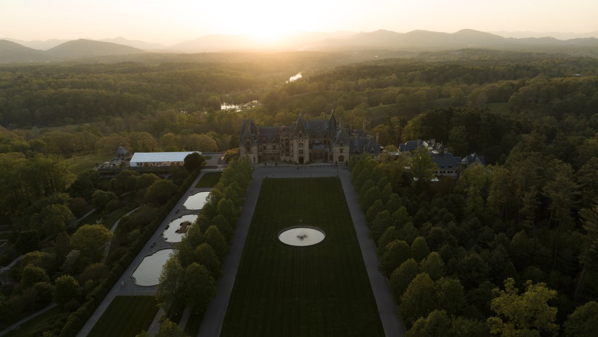 Aerial of vast Biltmore grounds and estate with mountains in background