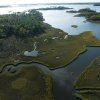 Aerial of kayaker paddling through meandering marsh in coastal forest