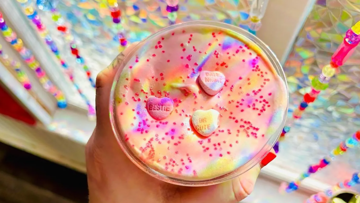 Closeup of colorful coffee being held in front of sparkly window decorations