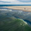 Person fishing from shore on empty beach