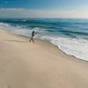 Man casting a line into ocean from shore during daytime