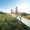 Couple walking bikes on wood walkway through marsh on Bald Head Island