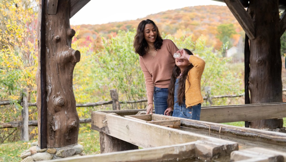 Mom and daughter at gem mine looking at rocks with fall foliage in background