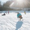 Person riding down mountain on adaptable skis with people on slope in background