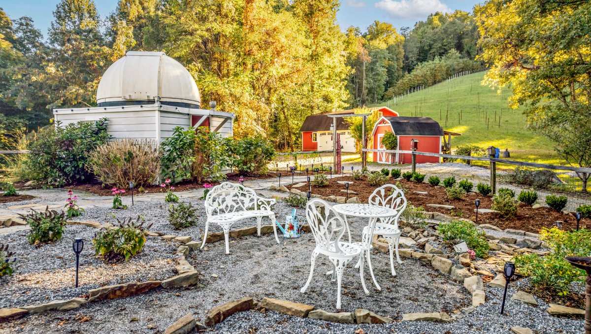 Bench and bistro set in serene garden on farm with trees in background