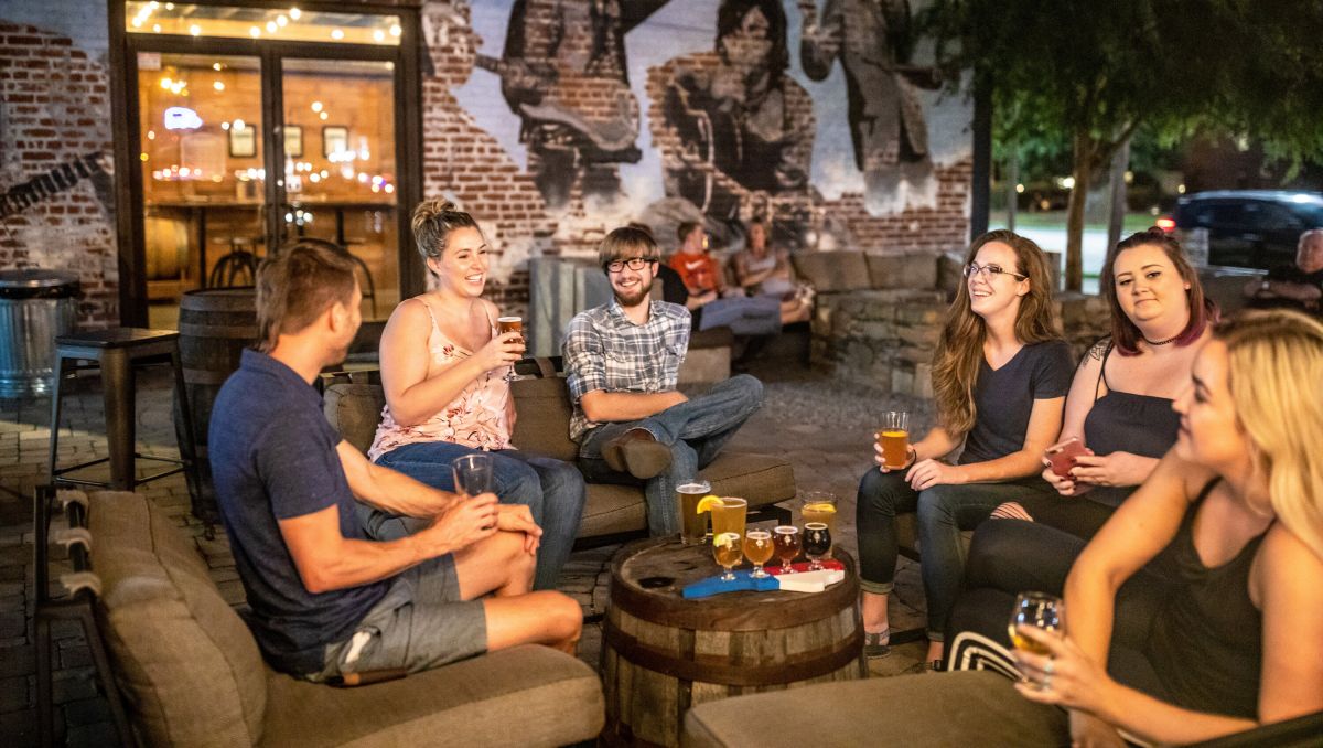 Friends talking and drinking beer around a beer barrel on outside patio at Brown Truck Brewery in High Point