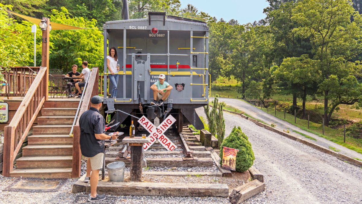 People hanging out on train-like vacation rental surrounded by green trees