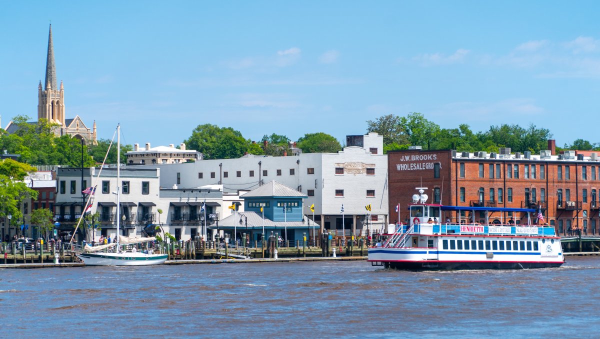 Riverwalk in distance with tour boat on water in foreground