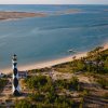 Aerial view of Cape Lookout Lighthouse in foreground with land and water in background during daytime