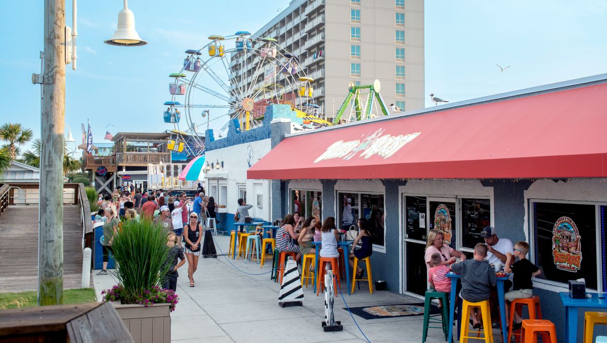 People mingling on boardwalk Carolina Beach boardwalk during daytime with Ferris wheel in background