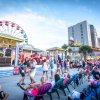 People sitting and dancing while watching band perform on colorful seaside boardwalk