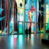 Two friends admiring large stained glass wall in museum