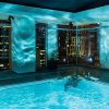 Man relaxing in corner of indoor pool at hotel with Charlotte buildings in background