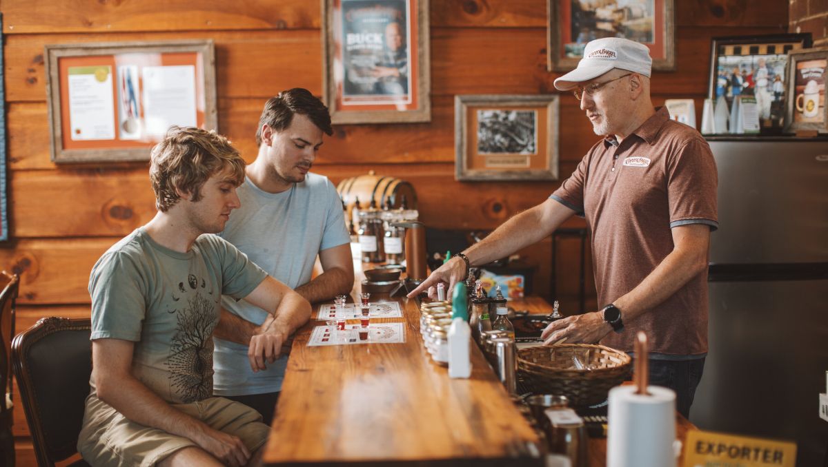 Two friends tasting various spirits at bar with bartender at Copper Barrel Distillery