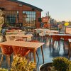 Tables and chairs on restaurant's rooftop during daytime with brick building in background