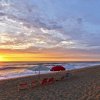 Beach chairs and umbrellas set up on empty beach as sun rises