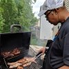 Man grilling meat and looking down at grill in backyard