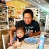 Father sitting with daughter giving thumbs up to camera in an art studio