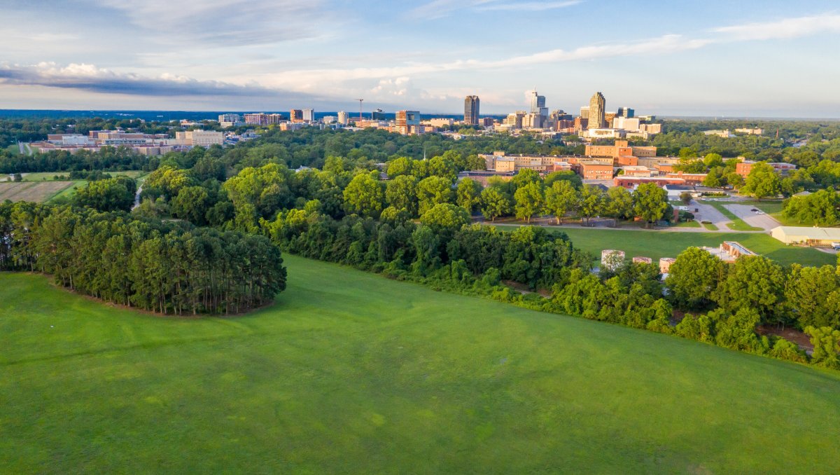 Aerial view of Dorothea Dix Park with Raleigh skyline in distance during daytime