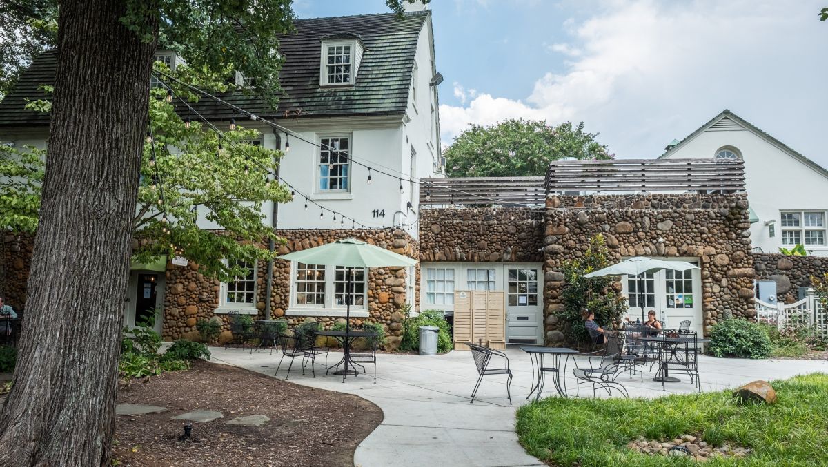 Two people sitting at table on patio outside farm-style house