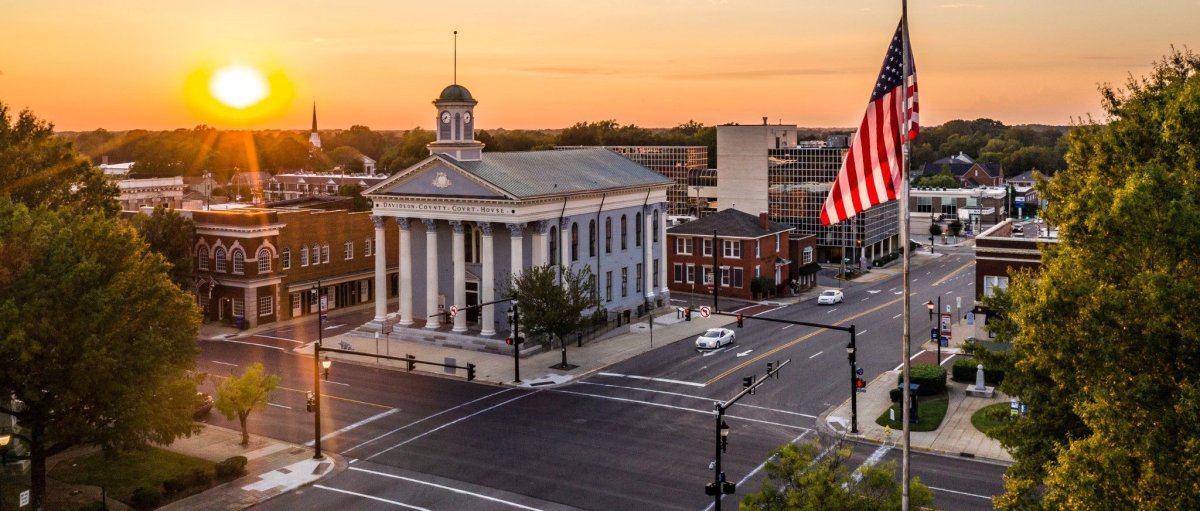 Aerial of downtown Lexington and courthouse at sunset with American flag in foreground