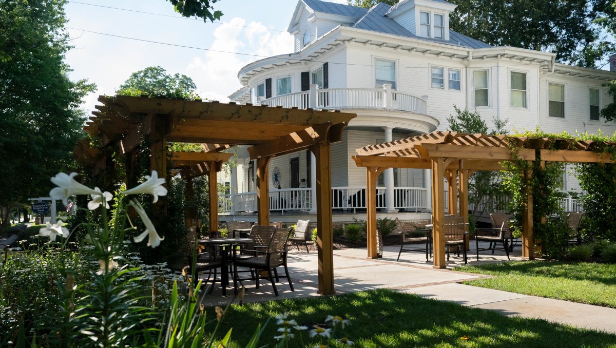 Wood pergolas outside in garden with beautiful white B&B house in background