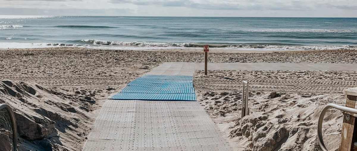 Accessible sand ramp going onto beach with ocean in background during daytime