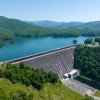 Aerial are large dam surrounded by mountains and green trees during daytime