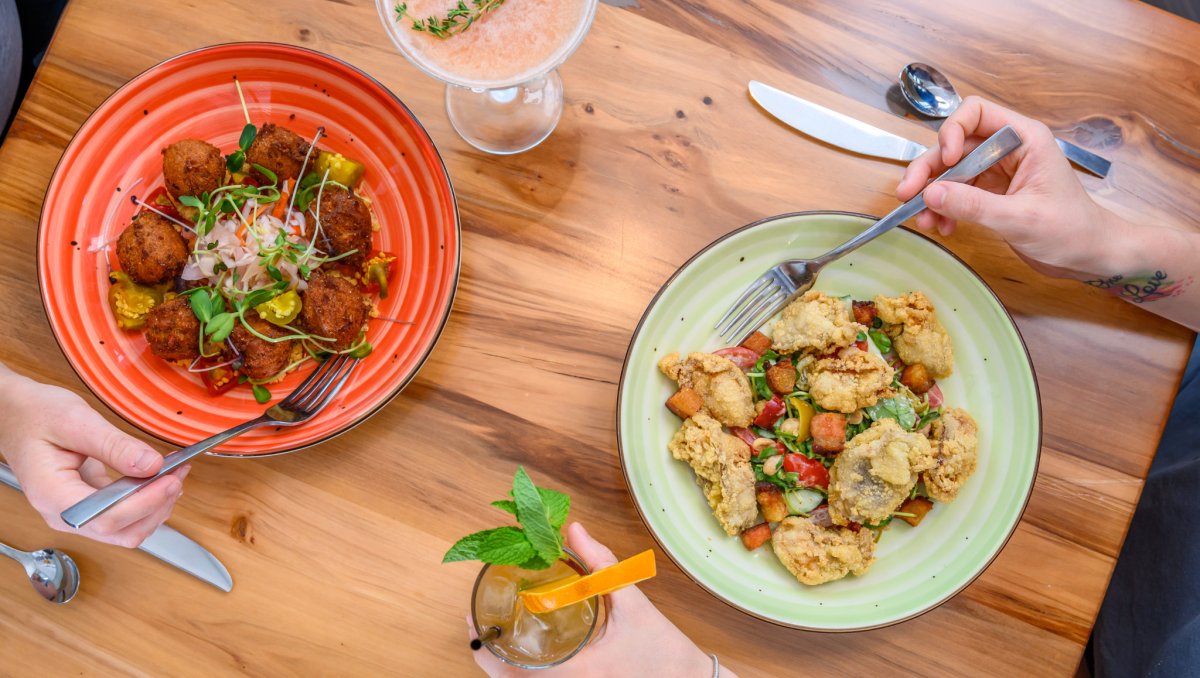 Overhead shot of two plates of food with drinks on wood table