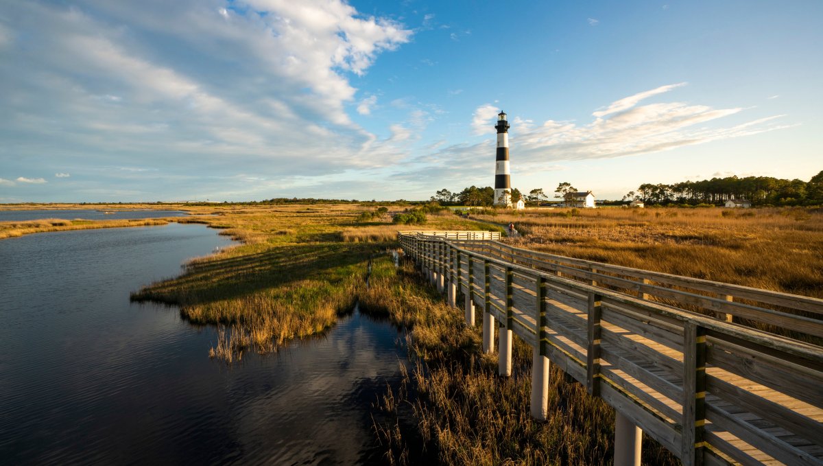 Golden sea oats, marsh and wooden walkway leading up to Bodie Island Lighthouse during daytime