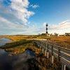 Golden sea oats, marsh and wooden walkway leading up to Bodie Island Lighthouse during daytime