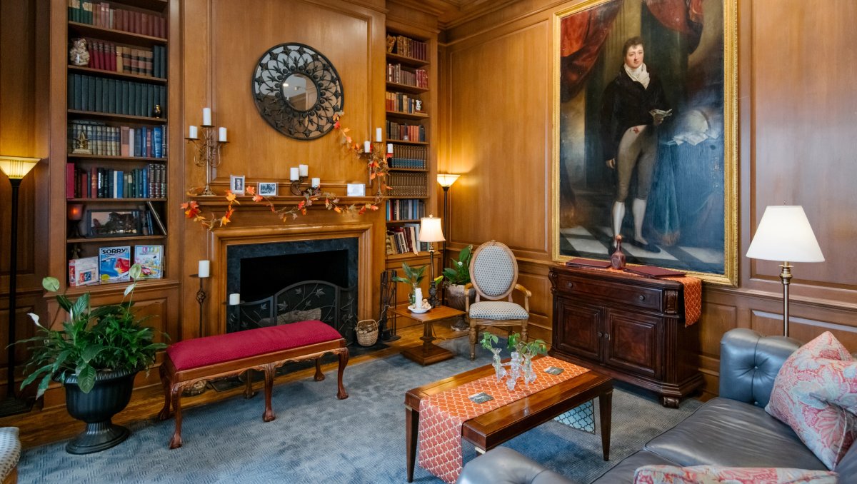 Interior of hotel lobby with art, bookshelves and fireplace