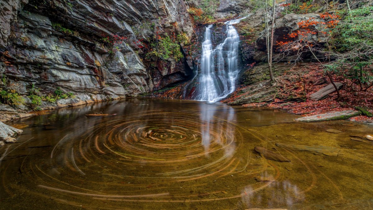 Waterfall cascading into water with intense fall foliage colors