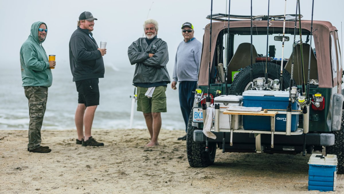 Surf fishermen by a Jeep in morning fog at the point in Buxton