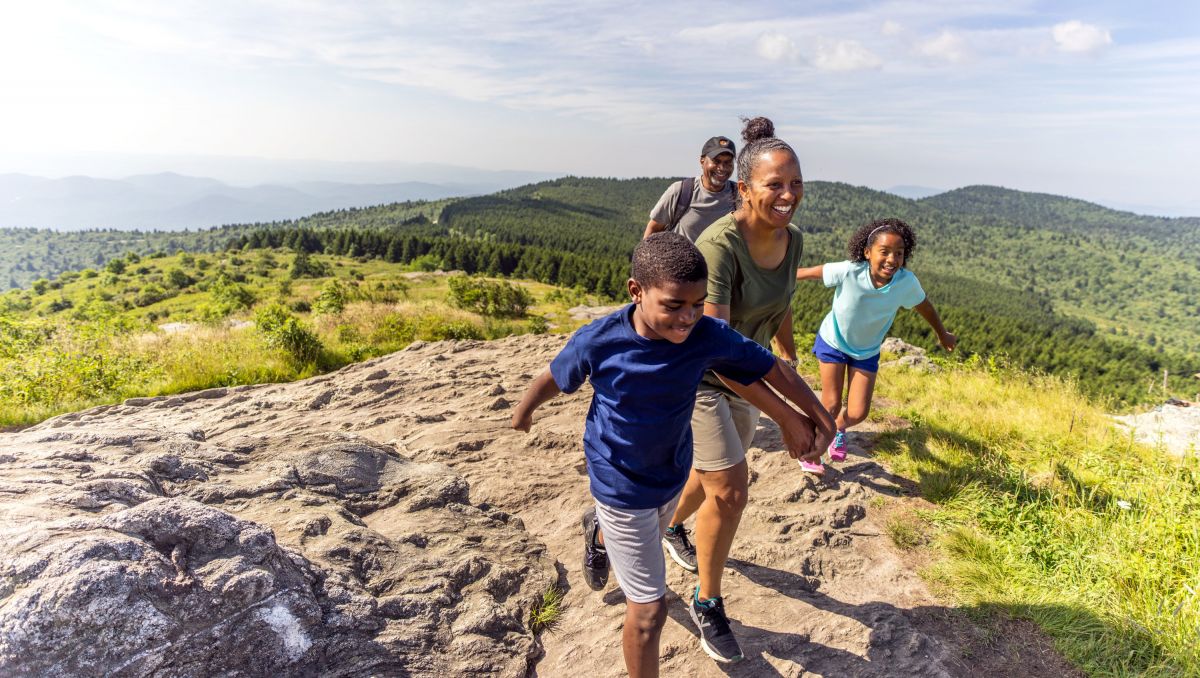 Family of four climbing up Black Balsam Knob on sunny day