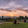 People sitting at lookout watching sunset over mountains in distance