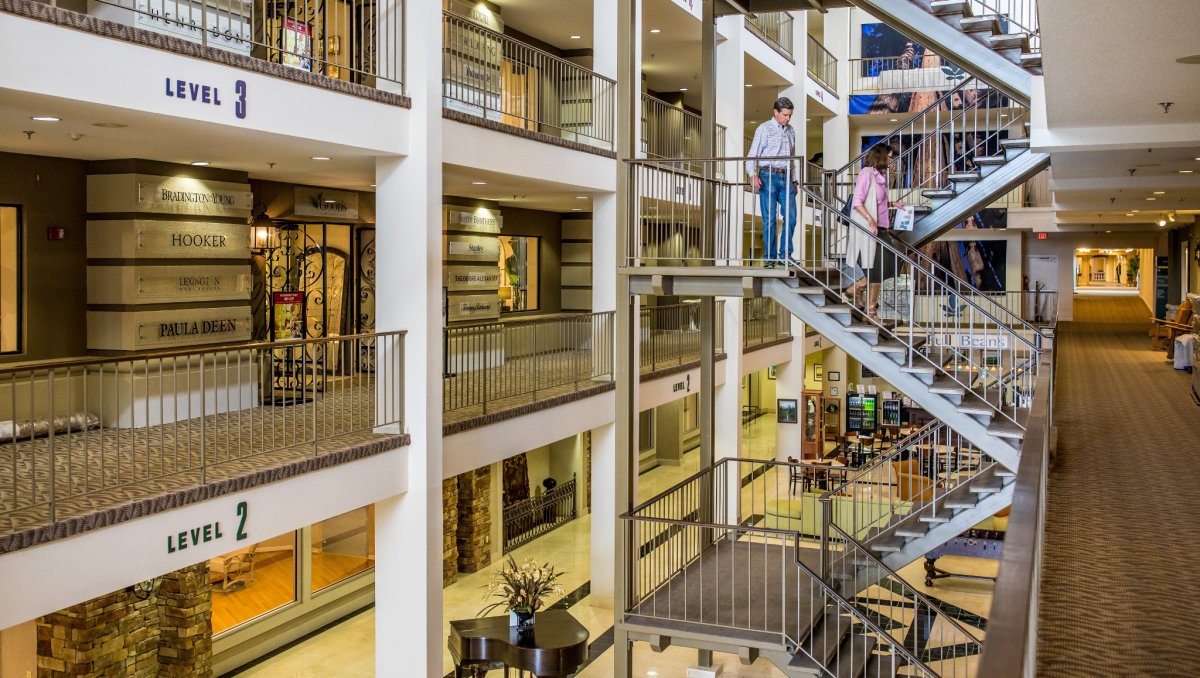 Hickory Furniture Mart interior with several floors, visible signage for levels 2 and 3, various shops and two people walking down a metal staircase