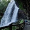 Woman standing in walking path behind and under large waterfall