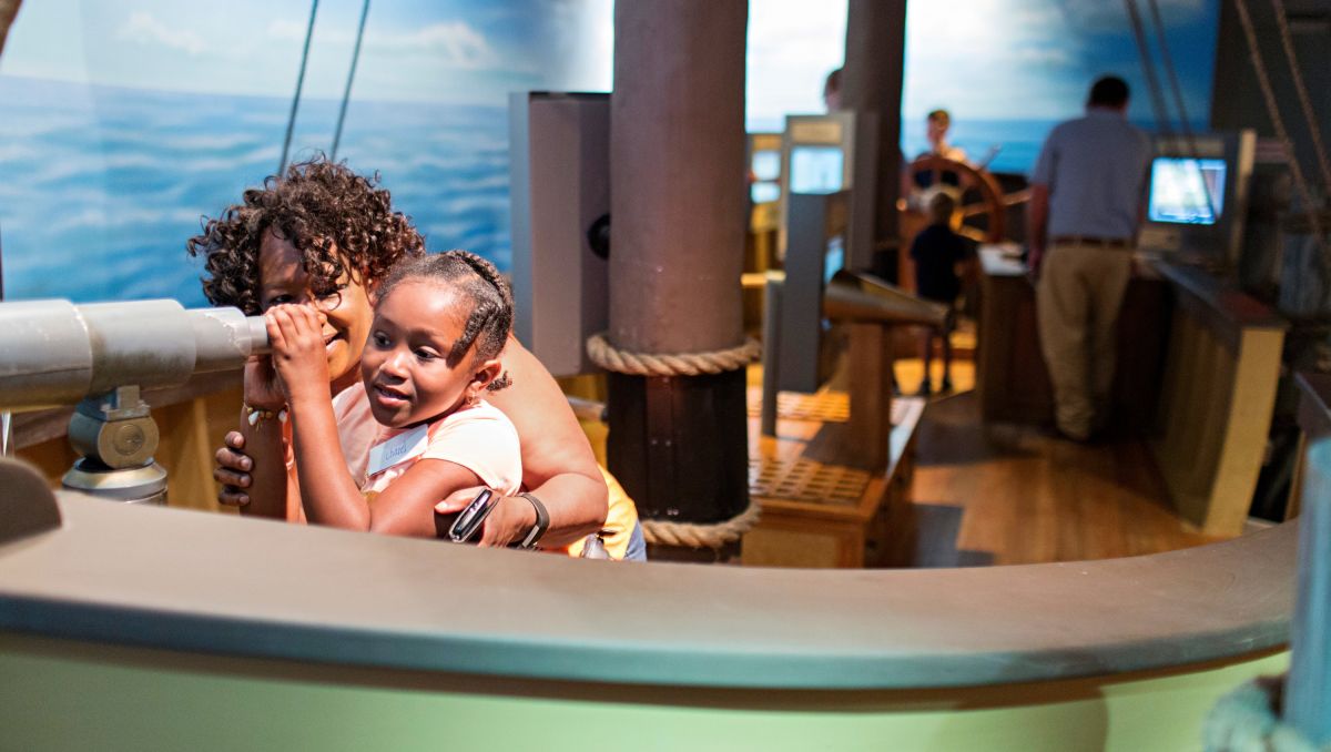 Mother and daughter looking through telescope at North Carolina History Center