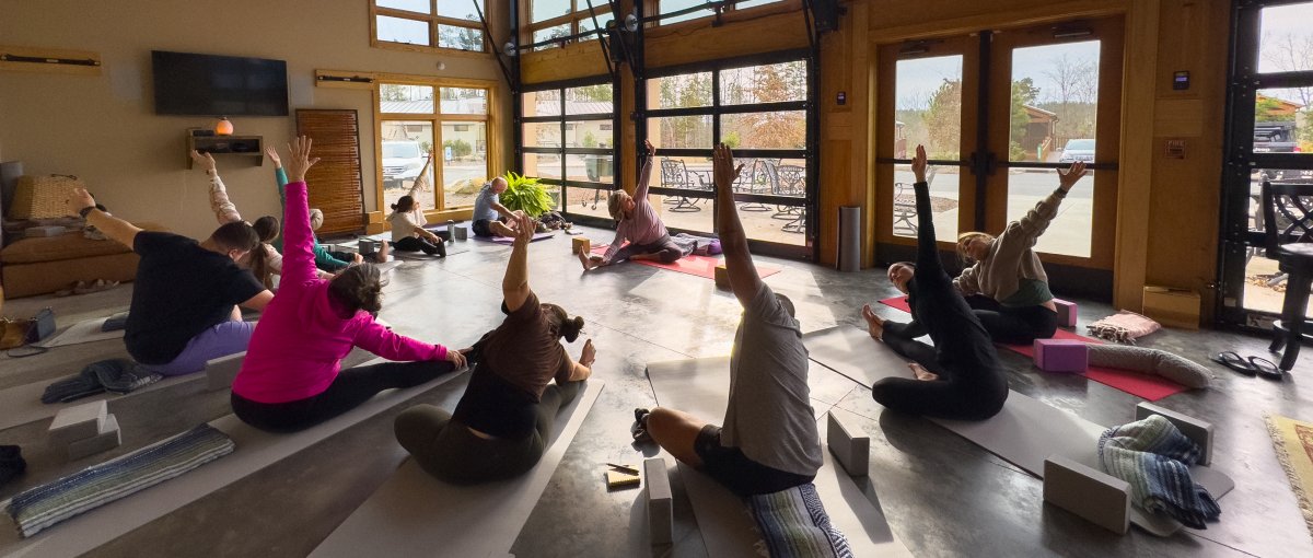 People on floor doing yoga in half circle with instructor in front