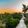 Sandy trail through brush and bushes in state recreation area under orange sky