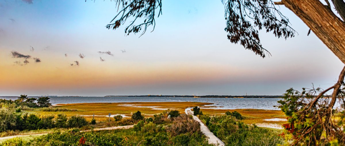 Long-range shot of marsh, water and trails under pretty sky