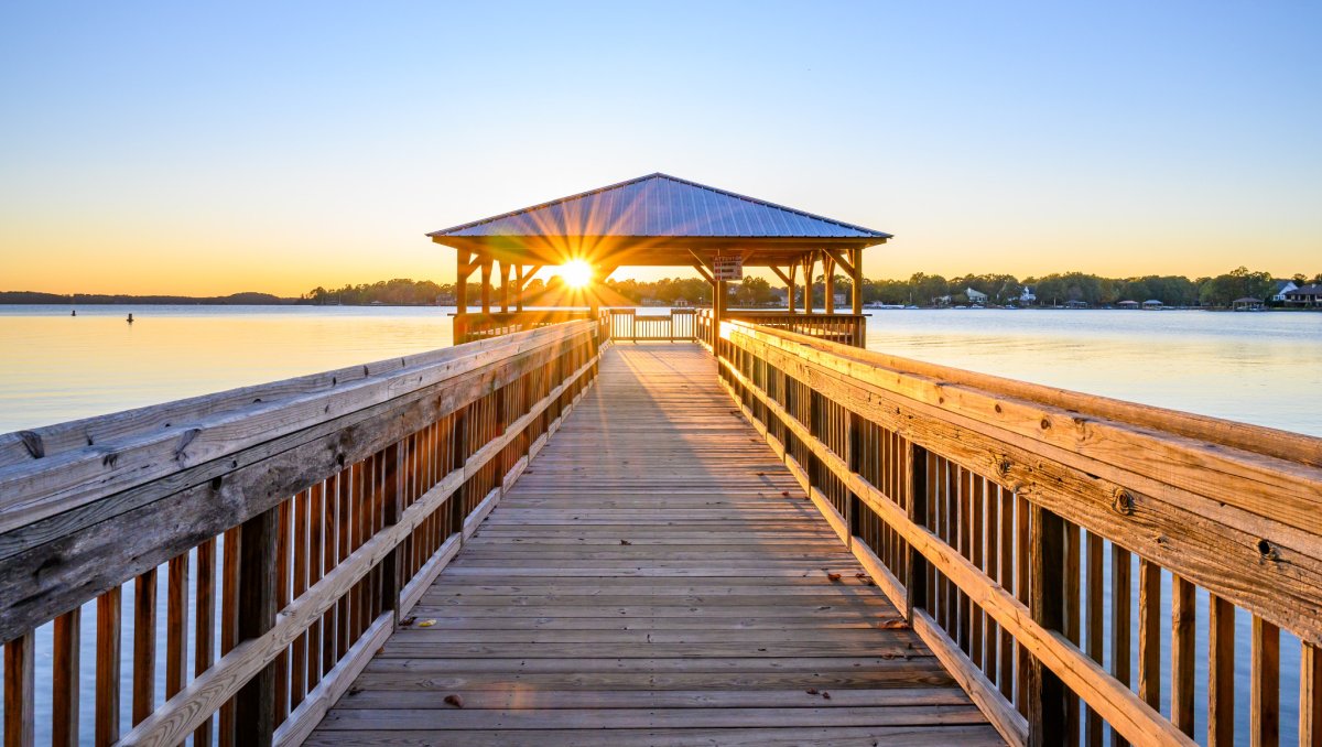 Gazebo jutting out into lake with sun shining into camera