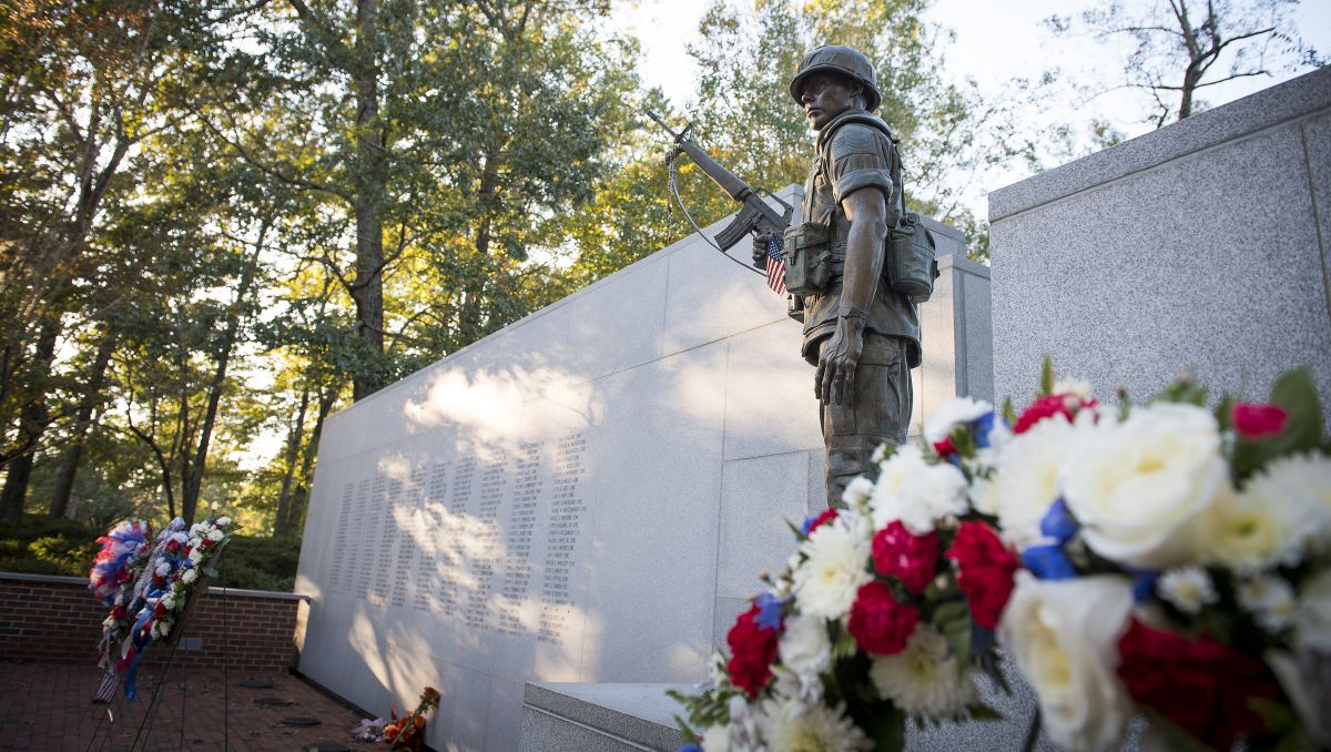 Military statue and monument with flowers in foreground during daytime